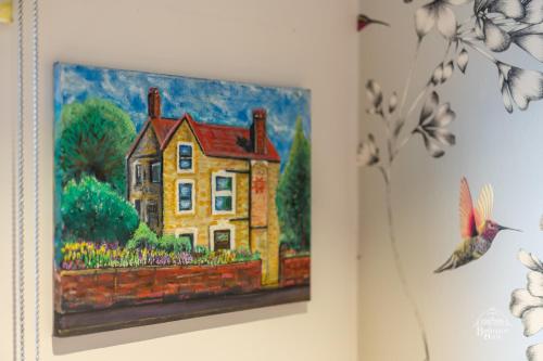 a painting of a yellow house on a wall at Burlington House Boutique in Oxford