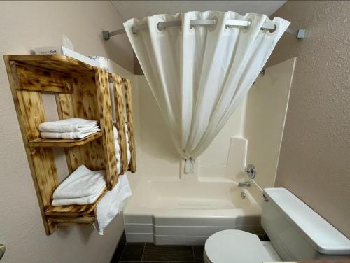 a bathroom with a tub and a toilet and a mirror at Glendive Lodge in Glendive