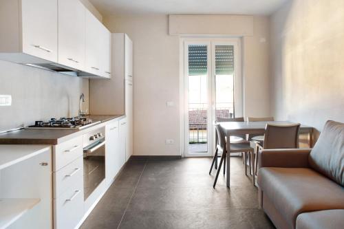 uma cozinha com armários brancos e uma mesa e cadeiras em Casa Maria Eugenia em Levanto