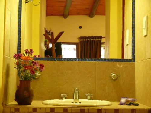 a bathroom sink with a mirror and a vase of flowers at La Casa del Tata in Maimará
