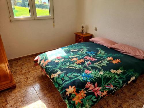 ein Schlafzimmer mit einem Bett mit einer bunten Decke in der Unterkunft Preciosa Casa de Campo + Playa + Jardín + Mascotas in Naveces