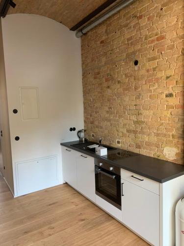 a kitchen with white cabinets and a brick wall at Stylisches Loft mitten in Berlin in Berlin