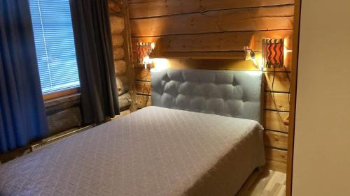 1 dormitorio con 1 cama en una pared de madera en Rukan Otsolanhovi en Ruka