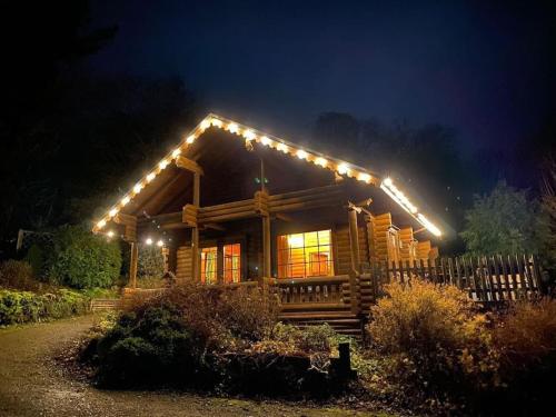 eine Blockhütte mit Nachtlicht auf dem Dach in der Unterkunft Countryside 3 Bedroom Log Cabin With Private Hot Tub - Ash in Leominster