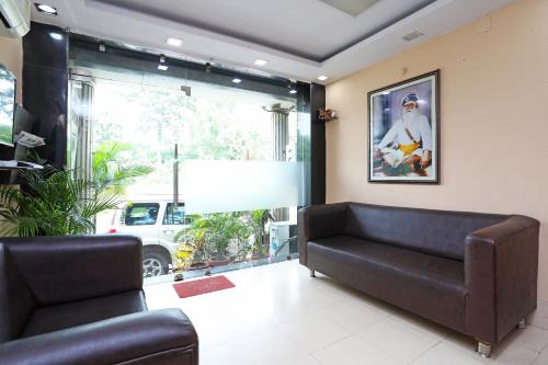 a living room with a couch and a large window at Collection O Hotel Greenpark in Jamshedpur