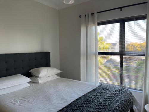 a bedroom with a bed and a large window at Luxury one bedroom apartment in Somerset West
