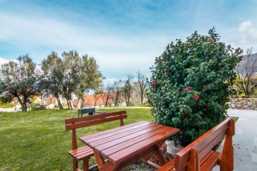 a wooden bench sitting next to a bush at Apartments Savić in Herceg-Novi