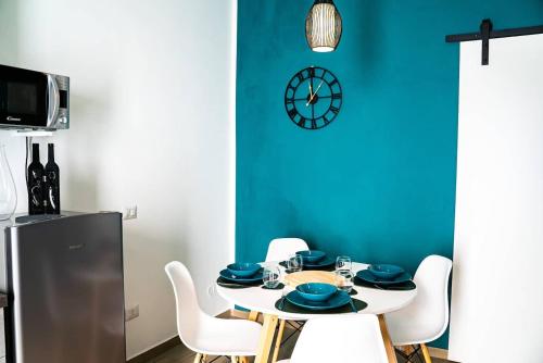 un comedor con una mesa con sillas blancas y un reloj en Luxury GreenHouse Napoli-Sorrento-Pompei en San Vitaliano 