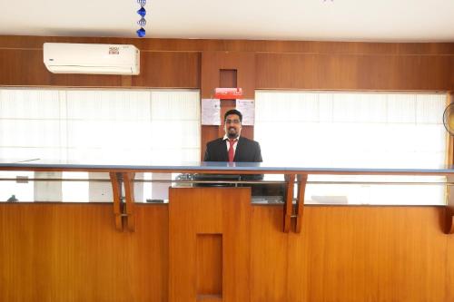 Een man in een pak aan een bureau in een kantoor. bij Super Capital O Hotel Dona Castle in Kollam