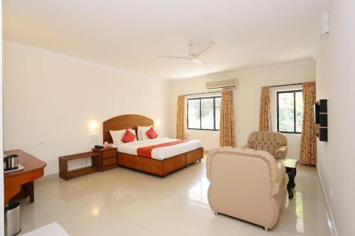 een slaapkamer met een bed, een bureau en een stoel bij Super Capital O Hotel Dona Castle in Kollam