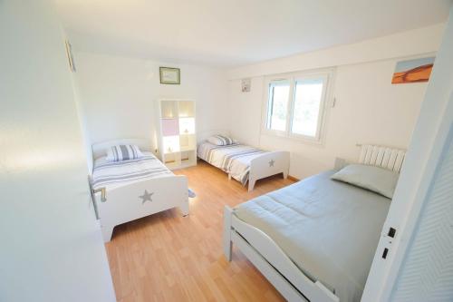 a white bedroom with two beds and a window at Villa de vacances moderne à côté de Bergerac in Prigonrieux