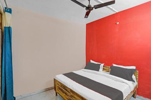 um quarto com uma cama com uma parede vermelha em Capital O Diamond 18 Near Worlds Of Wonder em Kālkāji Devi