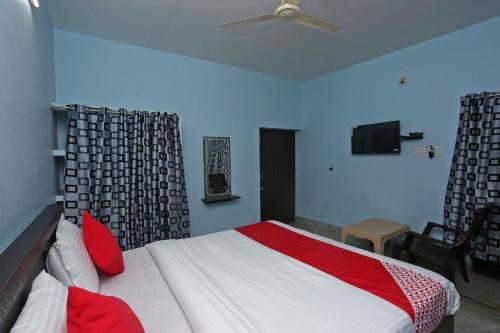 a bedroom with a bed with red pillows and a ceiling fan at Hotel O The Ambience in Bhubaneshwar