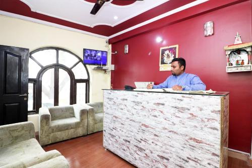 a man sitting at a counter in a room with red walls at Flagship Hotel Sweet Night in Ghaziabad