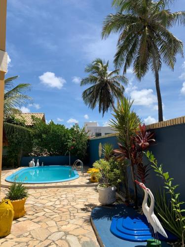 a swimming pool in a backyard with palm trees at Casa em condomínio, beira mar e piscina Barra de São Miguel - Maceió- AL in Barra de São Miguel