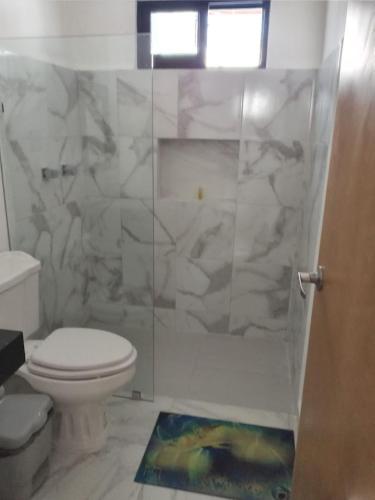 a bathroom with a toilet and a glass shower at Casa Flamingo Telchac in Telchac Puerto