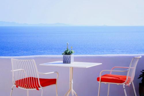 a table with two chairs and a table with a view of the ocean at VILLA NAUTILIA - Luxury Suites and Cottages in Kalafatis