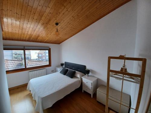 1 dormitorio con cama y techo de madera en Ático48, en Redondela