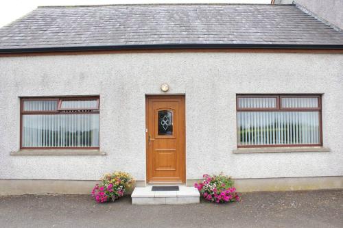 Casa blanca con puerta marrón y 2 ventanas en Carrick House, Mid-Ulster, en Knockcloghrim