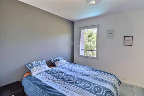 ein Schlafzimmer mit einem Bett mit blauer Decke und einem Fenster in der Unterkunft maison moderne en pleine nature, avec spa de luxe in Maringes