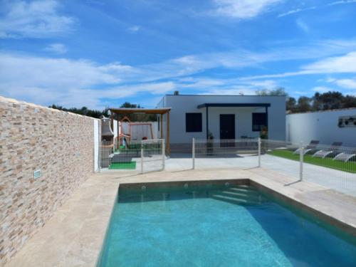 una piscina di fronte a una casa con muro di mattoni di Casa Rosalinda a Conil de la Frontera