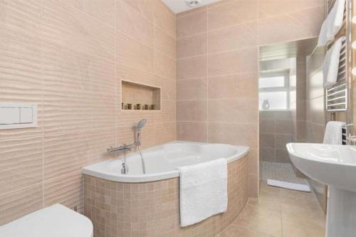 uma casa de banho com uma banheira e um lavatório em Edith Villas - Luxury seaside home with beautiful sea views-Pendine em Pendine