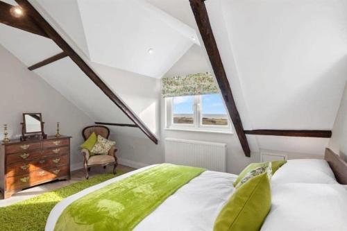 um quarto no sótão com uma cama e uma cadeira em Edith Villas - Luxury seaside home with beautiful sea views-Pendine em Pendine