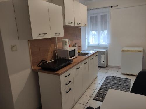 una cocina con armarios blancos y microondas en una encimera en Bristol Apartments 2, en Baja