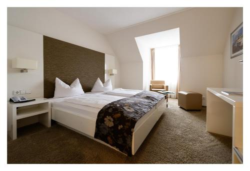 a bedroom with a large white bed and a window at Landhotel Burg im Spreewald - Resort & Spa in Burg