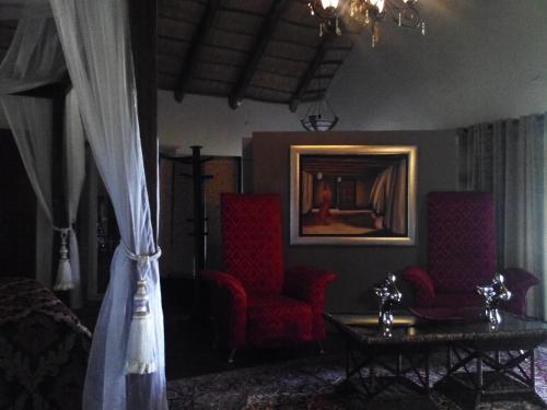 a living room with two red chairs and a table at Gabbata Lodge in Leeuwfontein