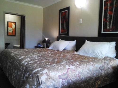 a bedroom with a large bed with white pillows at Gabbata Lodge in Leeuwfontein