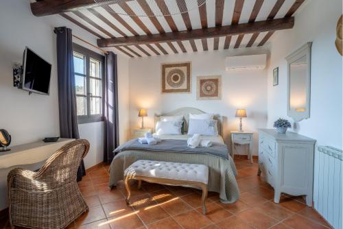 a bedroom with a bed and a chair and a tv at Bastide Rocquejeanne in Murs