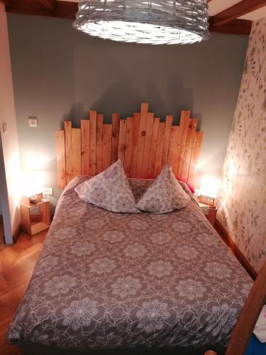 une chambre avec un grand lit avec une tête de lit en bois dans l'établissement La longére fleurie, à Cucq