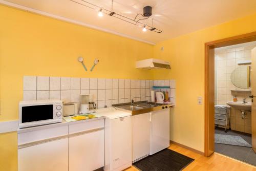 een keuken met gele muren, witte kasten en een magnetron bij Ferienwohnung Gernsbach in Gernsbach