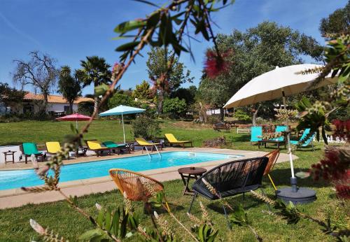 a pool with chairs and tables and an umbrella at Monte da Choça in São Teotónio