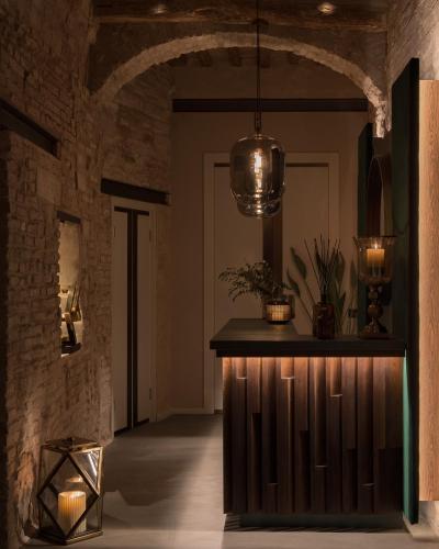 a hallway with a stone wall and a counter with lights at Times Suites in Perugia