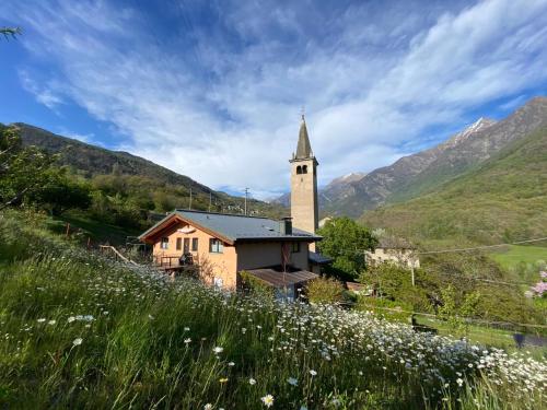 a church with a tower and a field of flowers at Maison d'hôtes Victoret in Challand Saint Victor
