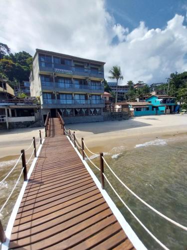 a building on the beach with a wooden boardwalk at Pousada toca do cambu in Angra dos Reis