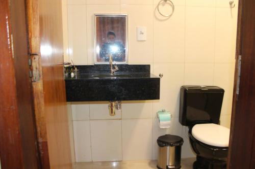 een man die een foto neemt van een badkamer met een wastafel bij Casa da Sueli in Foz do Iguaçu