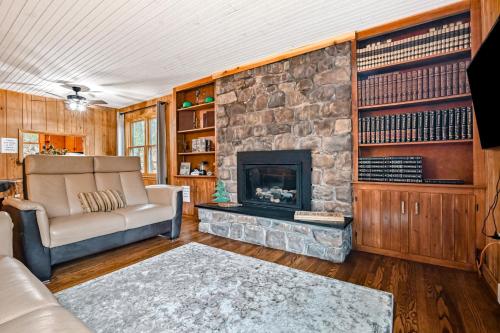 a living room with a stone fireplace and a couch at Woodland Cabin Retreat in Lake Harmony