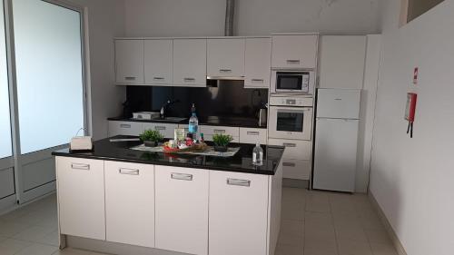 a kitchen with white cabinets and a black counter top at Apartamento Pérola da Vila in Vila Franca do Campo