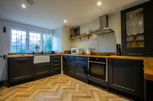 a kitchen with black cabinets and a wooden floor at The Potting Shed in Chepstow