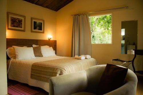 a bedroom with a bed and a chair and a window at Pousada Quinta do Barao in Conceição da Ibitipoca