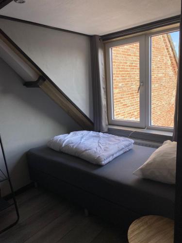 a small bed in a room with a window at huisje in zeeland helemaal gerenoveerd in Sint Annaland