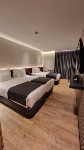 a hotel room with two beds and a television at Hotel Principe Avila in Lisbon