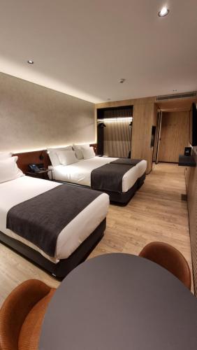 a hotel room with two beds and a table at Hotel Principe Avila in Lisbon