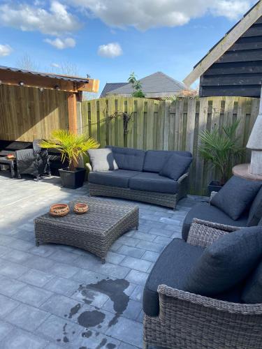 a patio with couches and chairs and a table at huisje in zeeland helemaal gerenoveerd in Sint Annaland