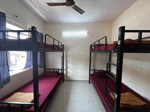 a room with three bunk beds and a ceiling fan at Lostel Gokarna in Gokarna