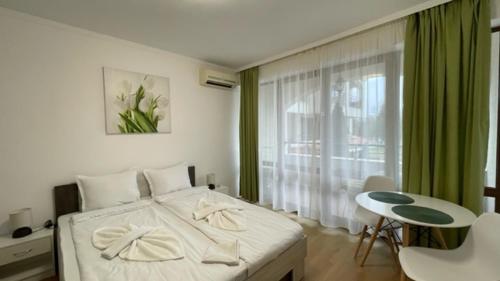 a bedroom with a bed and a table and a window at CHATEAU DEL MAR C31a Studio Sunny Beach in Sunny Beach
