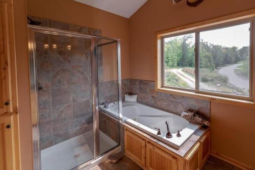 baño con bañera y ducha y ventana en Luxury Leech Lake Home 15 Minutes to Walker en Walker